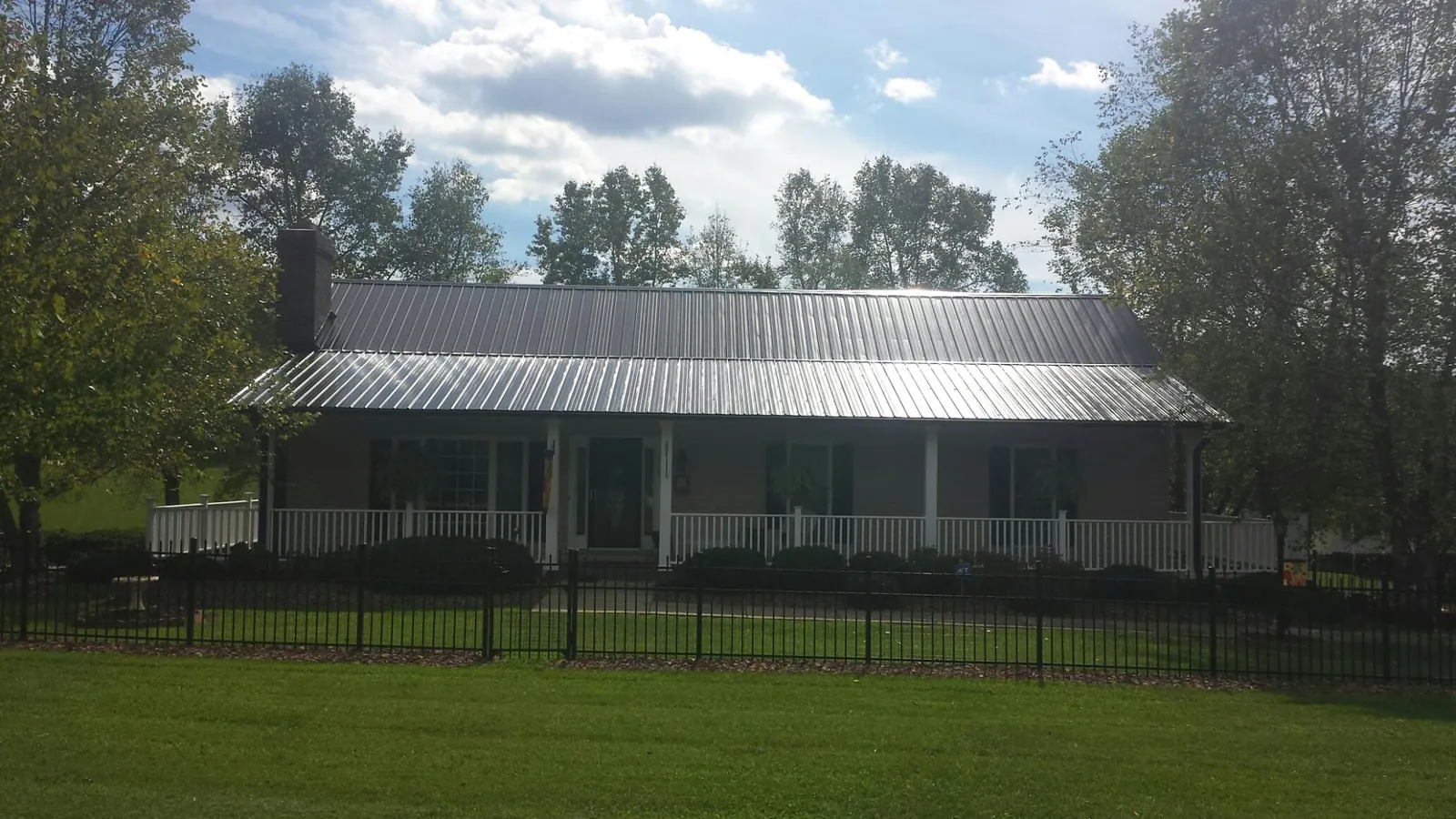 Gray metal roof on a brick ranch with a full width front porch — Gutter Guard Installation work by our crew in Baraboo