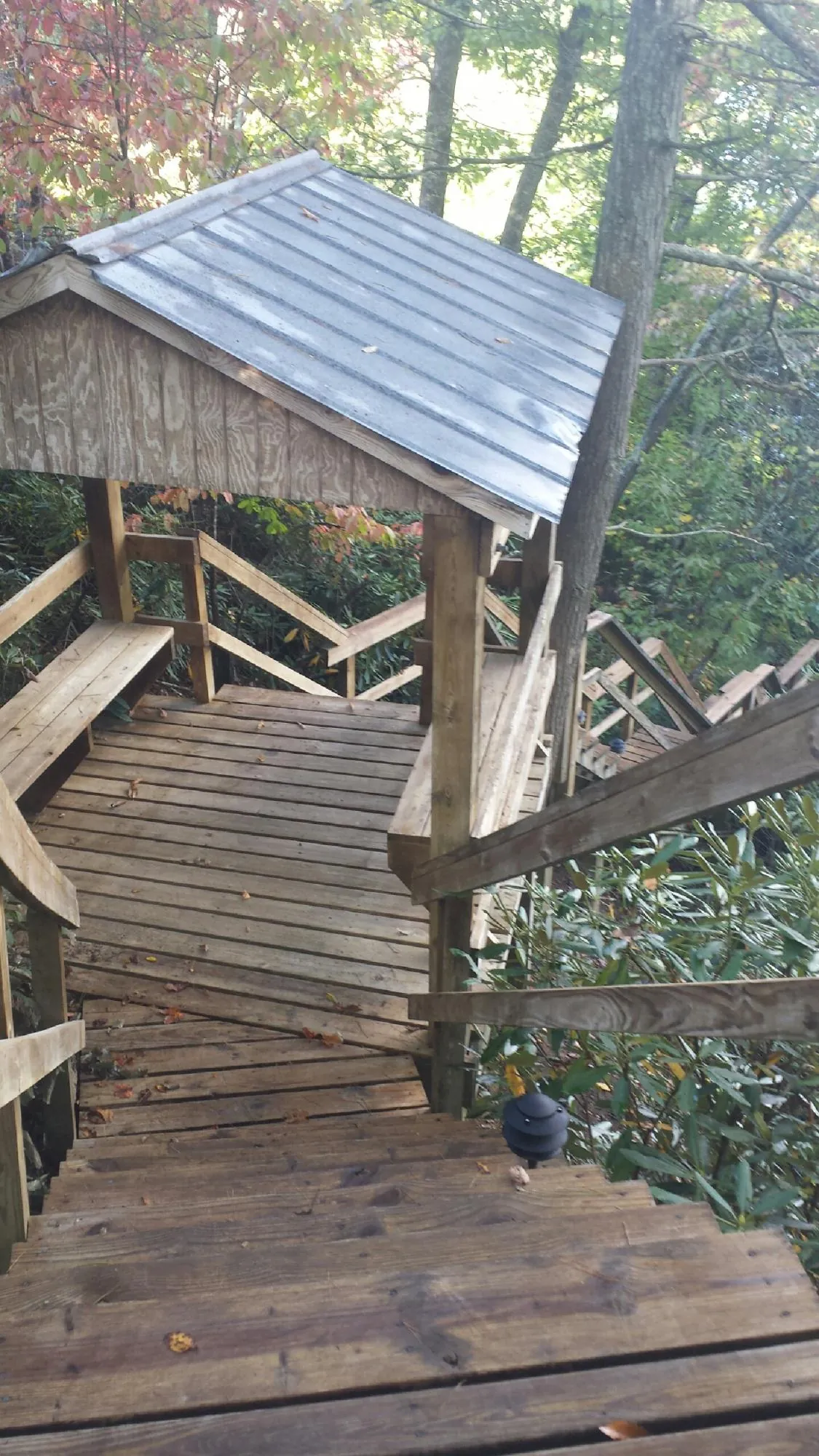 Metal roofed shelter over wooden steps on a wooded walkway — Skylight Repair & Installation work by our crew in Baraboo